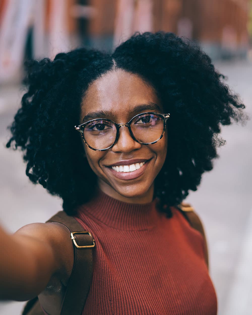 a person wearing glasses and smiling at the camera