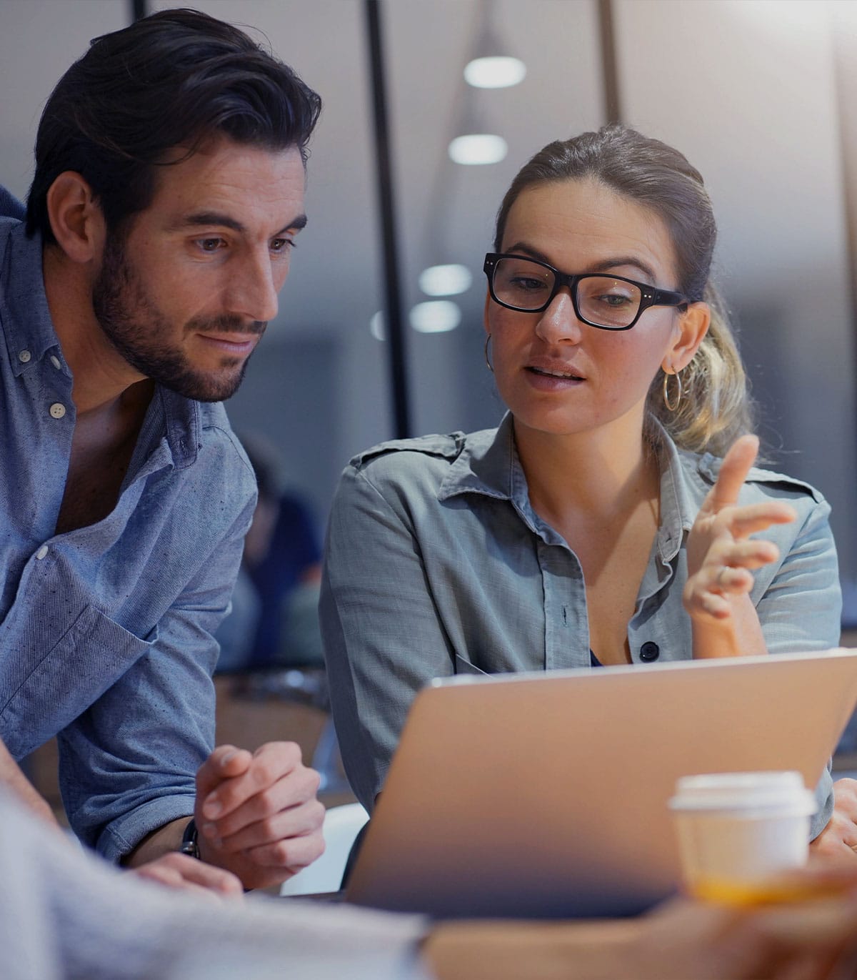 a group of people sitting at a table using a laptop computer